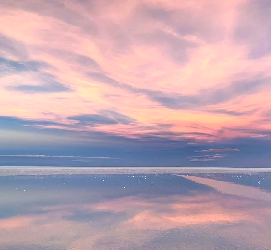 A wide pink sky reflected across still water.